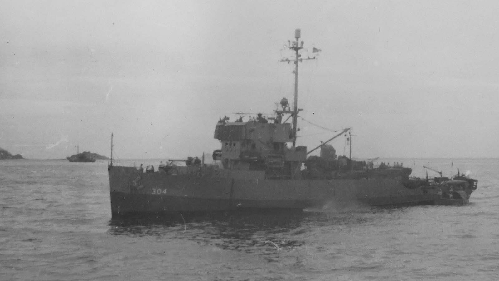 A photo in Bill McMillan’s scrapbook shows a destroyer escort in a coastal area. The number of the ship corresponds to the USS Rall.