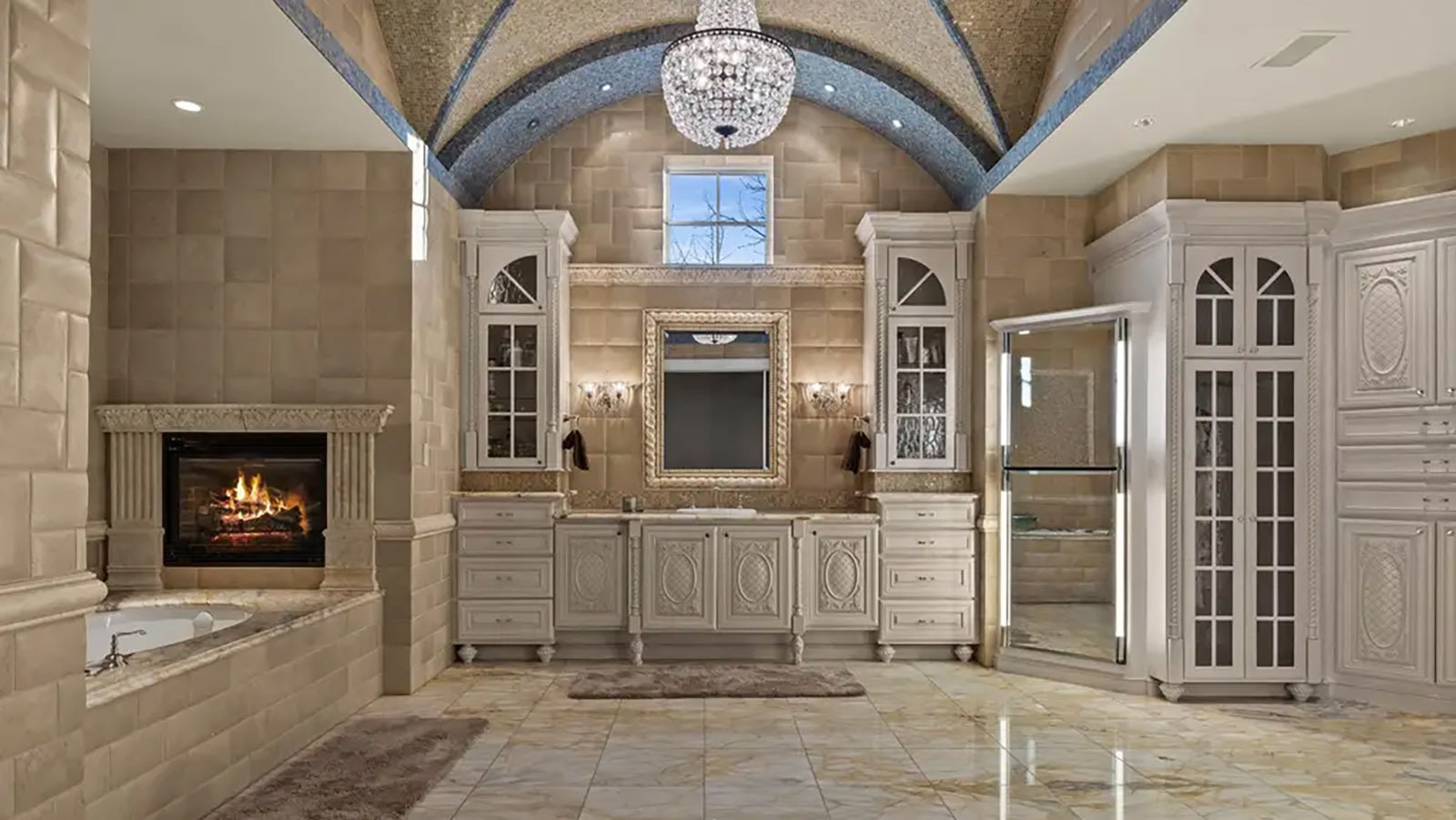 The master bathroom is large with double vanities, a fireplace above the bathtub and marble floors.