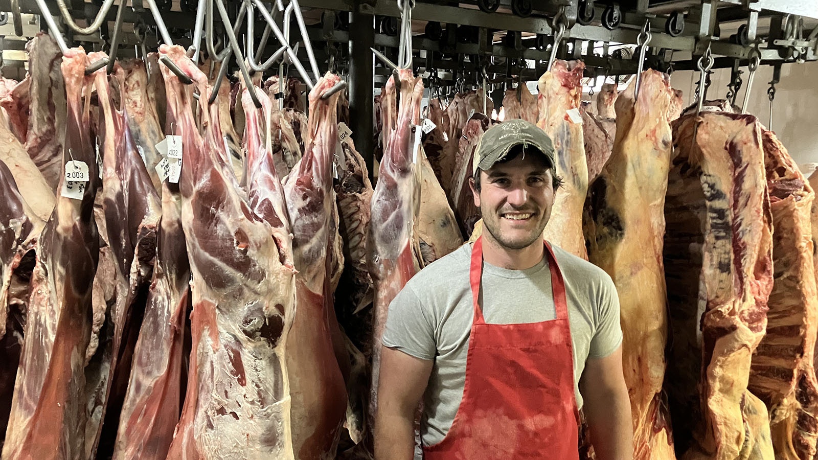 Craig Linden, owner of 307 Meats in Mills, Wyoming, stands in front of hanging meat curing at his facility.