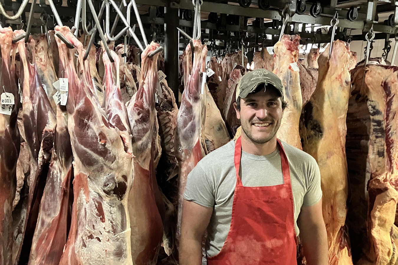 Craig Linden, owner of 307 Meats in Mills, Wyoming, stands in front of hanging meat curing at his facility.