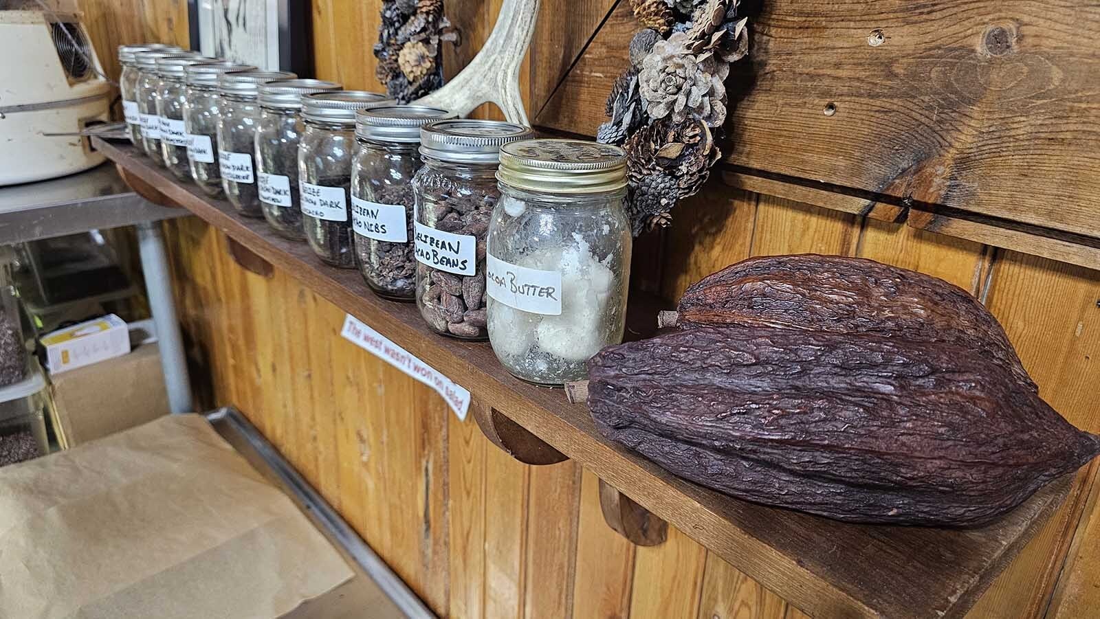 In front, two cacao pods, along with some cacao butter and various cacao beans.