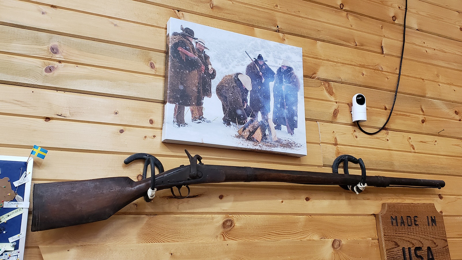 A photo of "The Hateful Eight" hangs on the wall of Merlin's Hide Out above an antique rifle found at an auction.