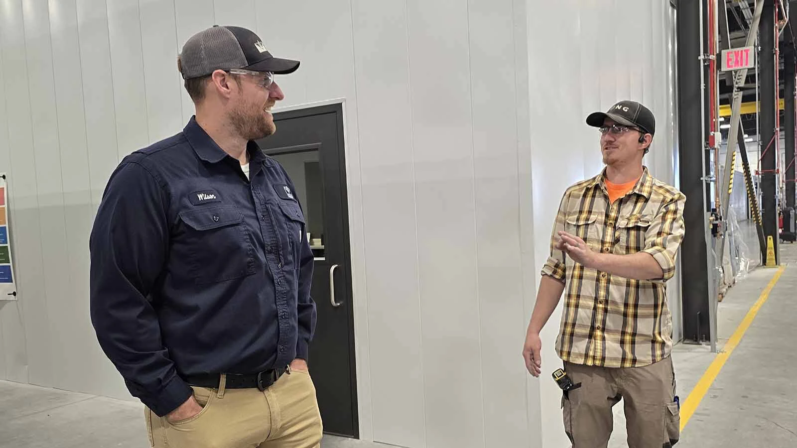 Mesa Power Solutions Director of Assembly Josh Wilson talks with an employee during a tour of the plant with Cowboy State Daily.