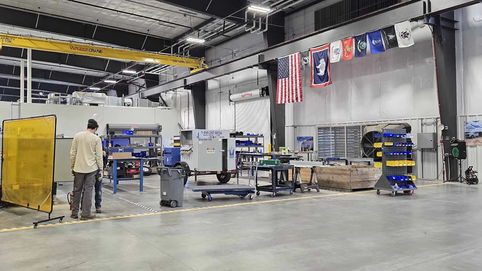 A number of military veteran flags hang in Mesa Power Solutions' new plant. About one-third of their workers are veterans.