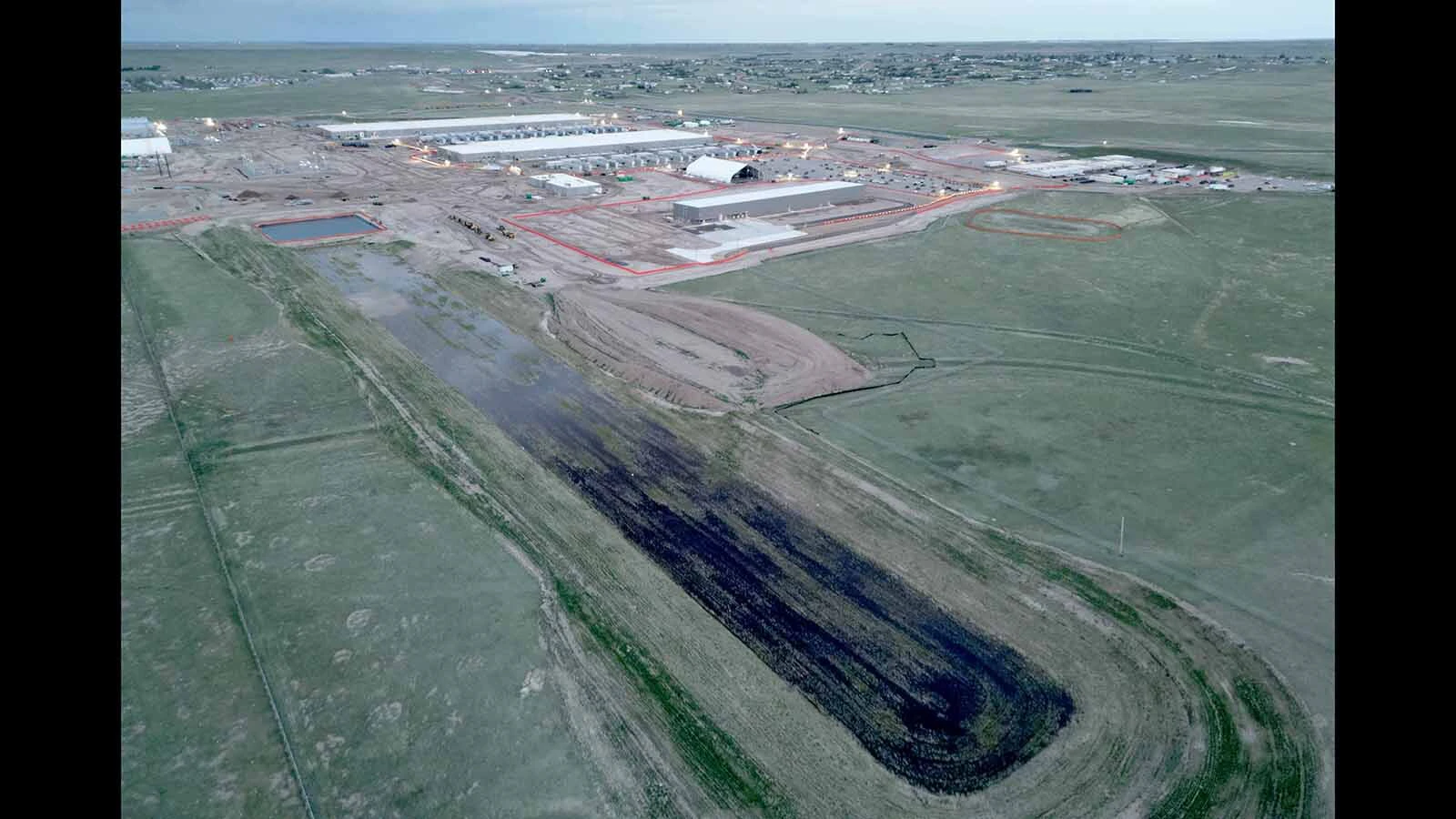 An aerial view of the Meta data center being built in south Cheyenne. A water pond is shown at the back end of a long collecting pool.