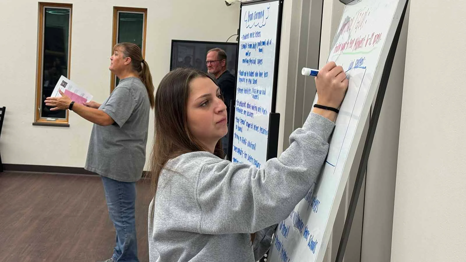 Logan Fleminger writes down points to highlight when Midwest residents lobby school board members to save their school's grades 6-12, which are on the chopping block.