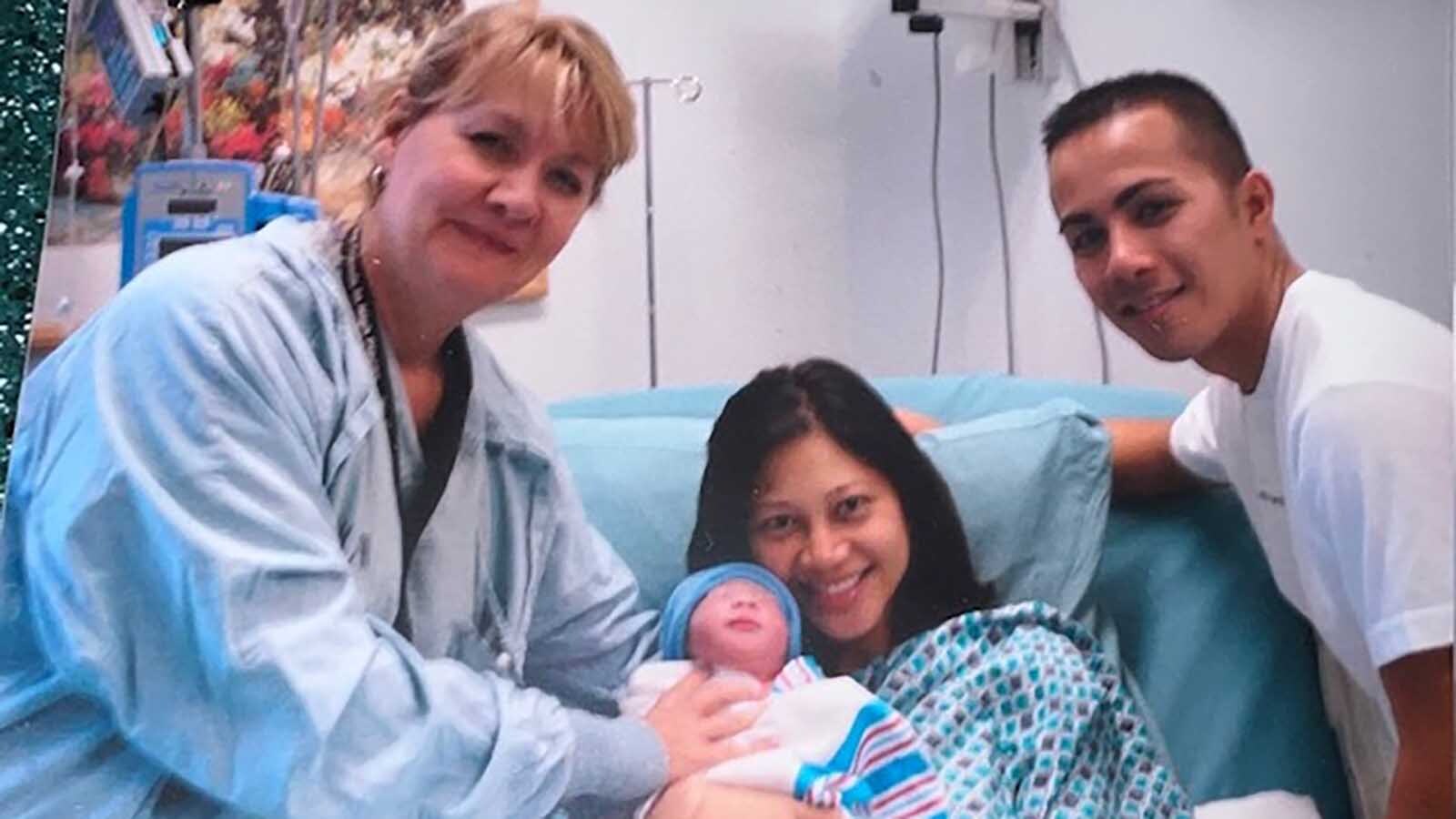 Helen LaRose poses with a newborn baby and its happy family just after the baby was born.