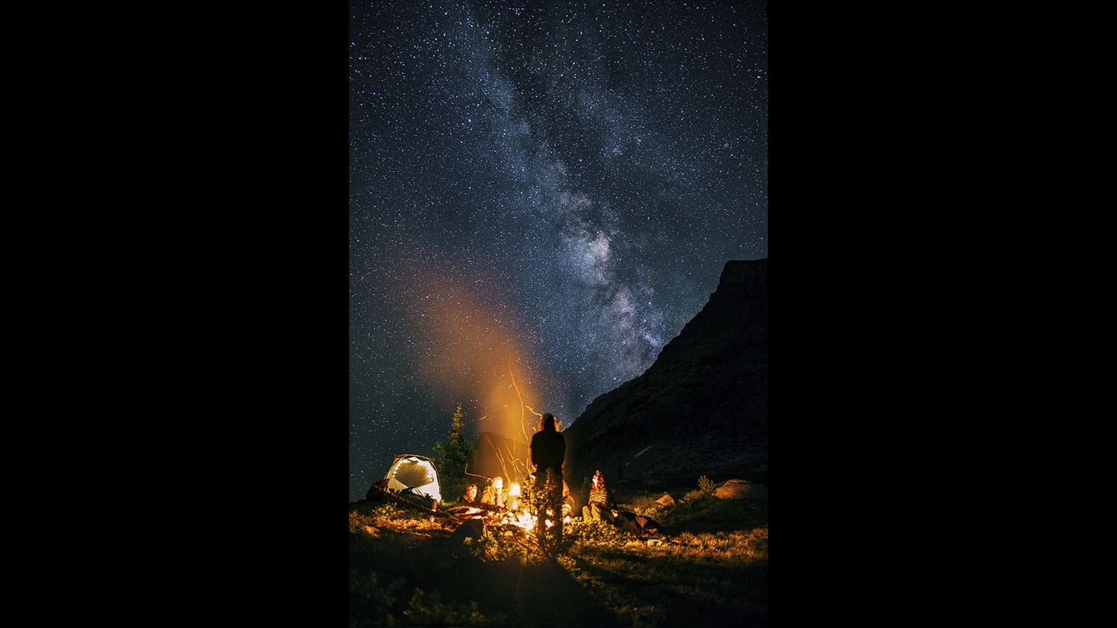 The Milky Way Galaxy as seen in the pristine night skies over Wyoming. This shot shows the light from a campfire on a backdrop of the Milky Way.