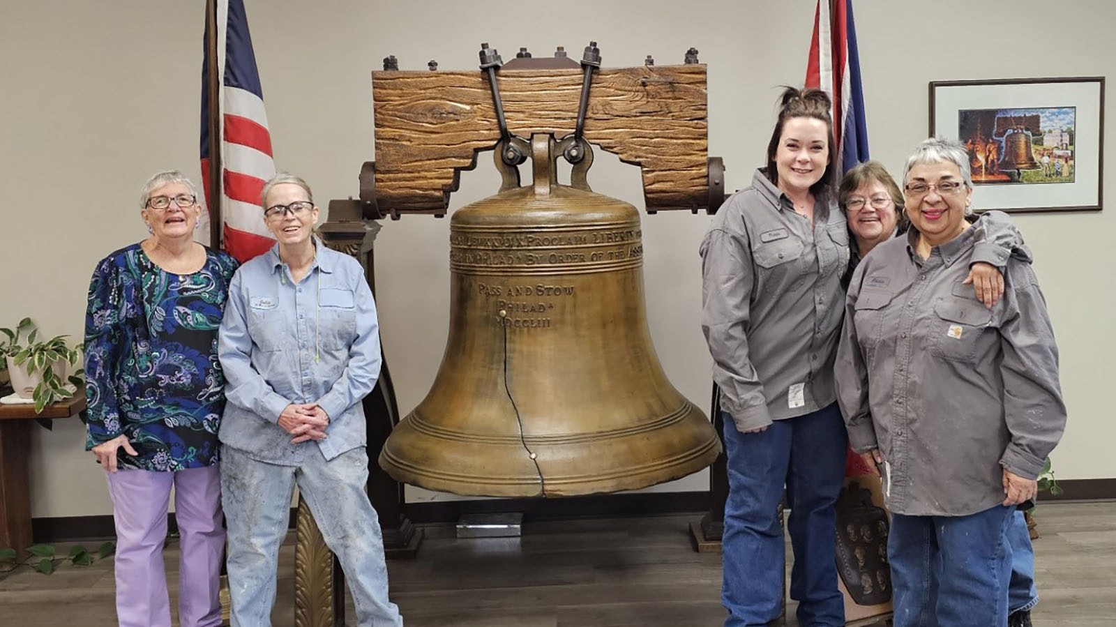 A group of Excel Inc. employees pose with and exact replica of the Liberty Bell in the office of the Mills, Wyoming, foundry.