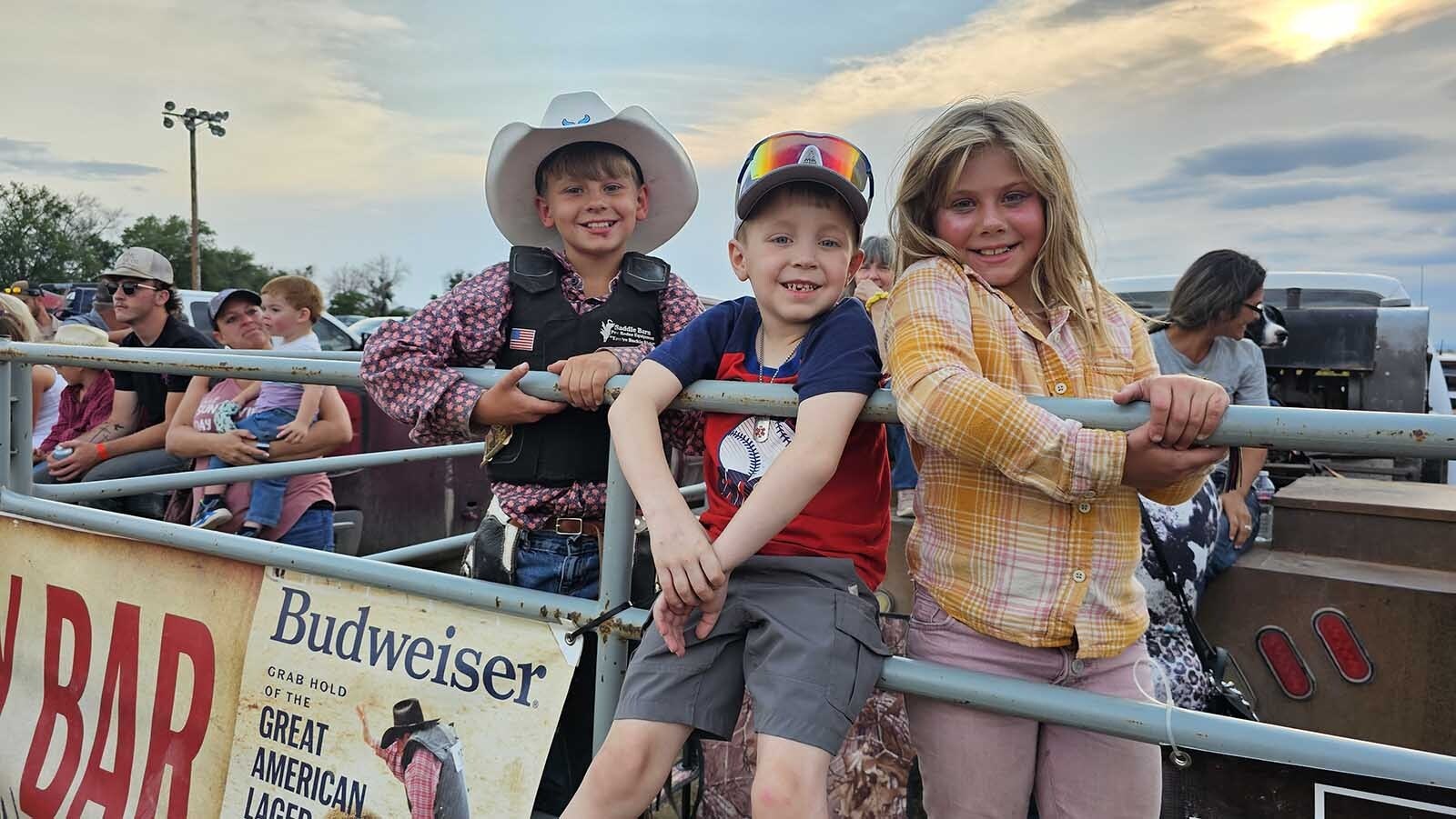 From left, Chase Heinrich, Korbynn Smith, and Aynsley Heinrich watching the rodeo action during a miniature roughstock rodeo in Newcastle during the Weston County Fair.