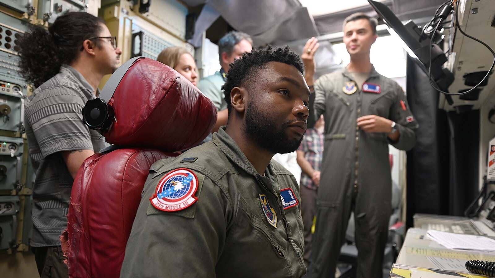 Lt. Josh Williams, seated, listens while his crewmate Lt. Harrison Martin speaks inside the control room.