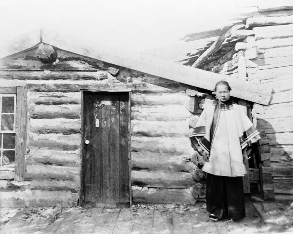 A Chinese woman in front of a log cabin, possibly Soo Liang, aka "Chinese Suisie" around 1899-1908.