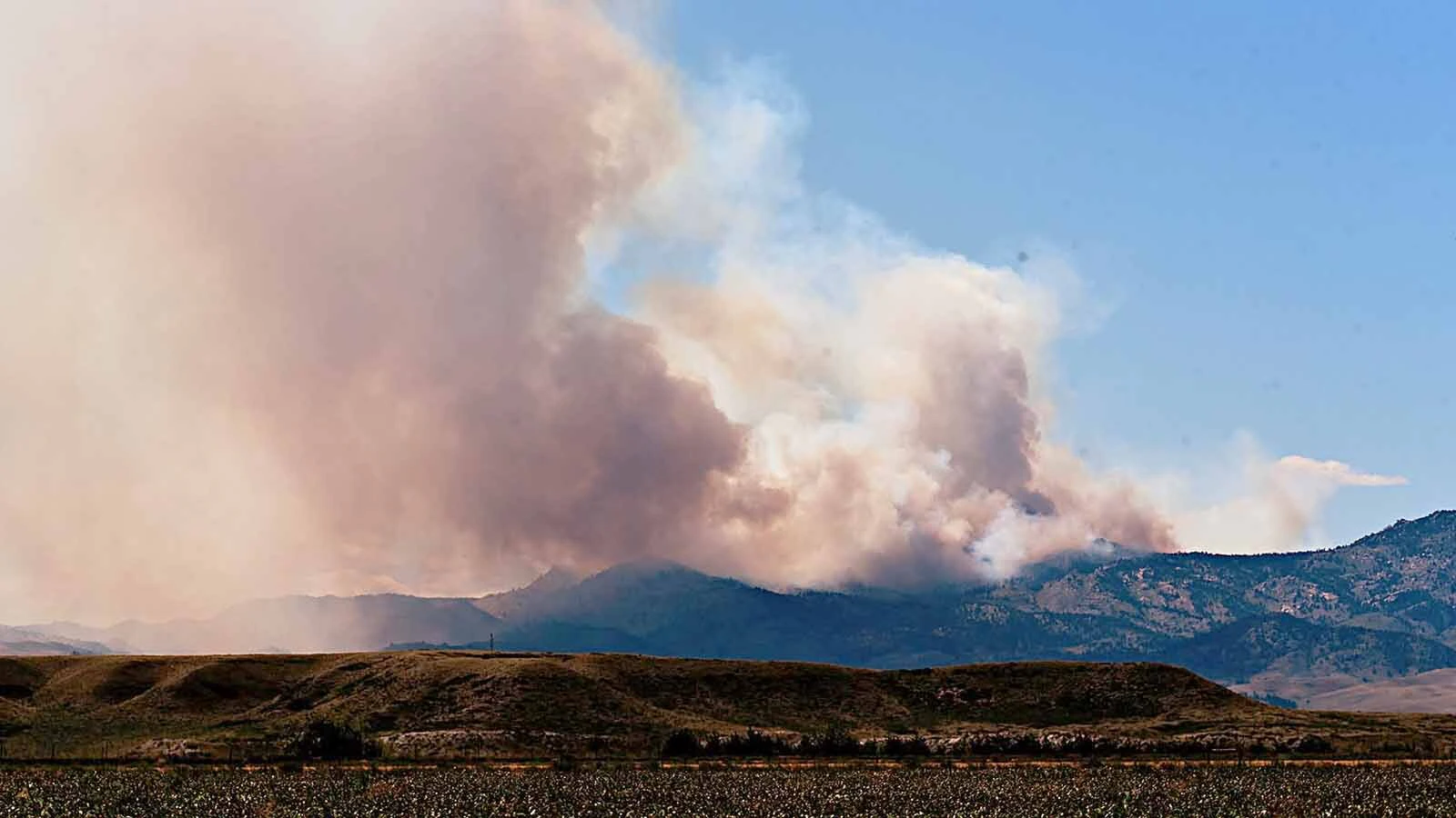 Smoke rises southwest of Wheatland, Wyoming, as the Moonshine Fire burns in rugged and remote terrain in northern Albany County.