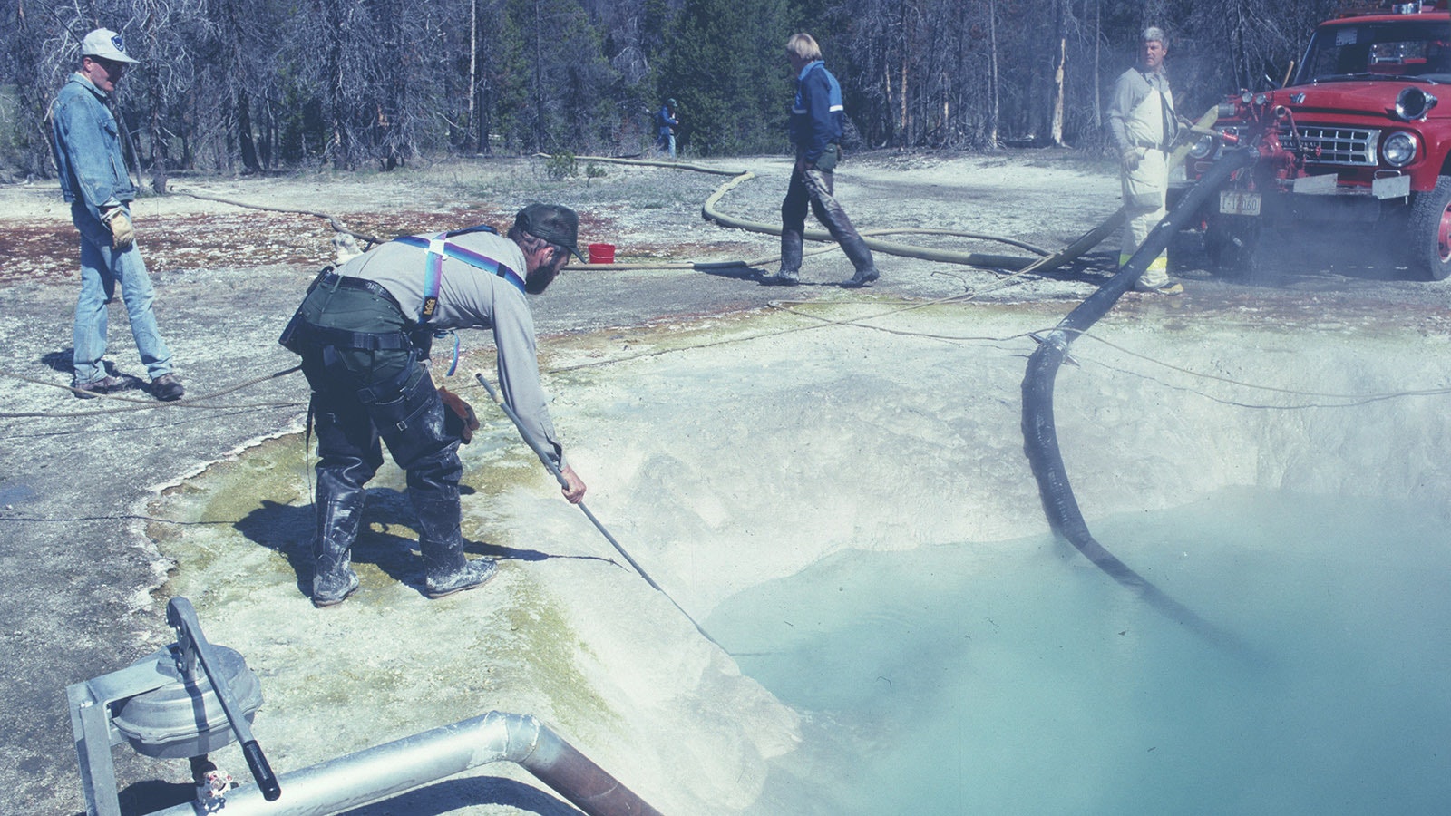 Rick Hutchinson uses a long-handled net while tethered with a climbing harness cleaning out Morning Glory Pool in Yellowstone National Park in June or July 1991.