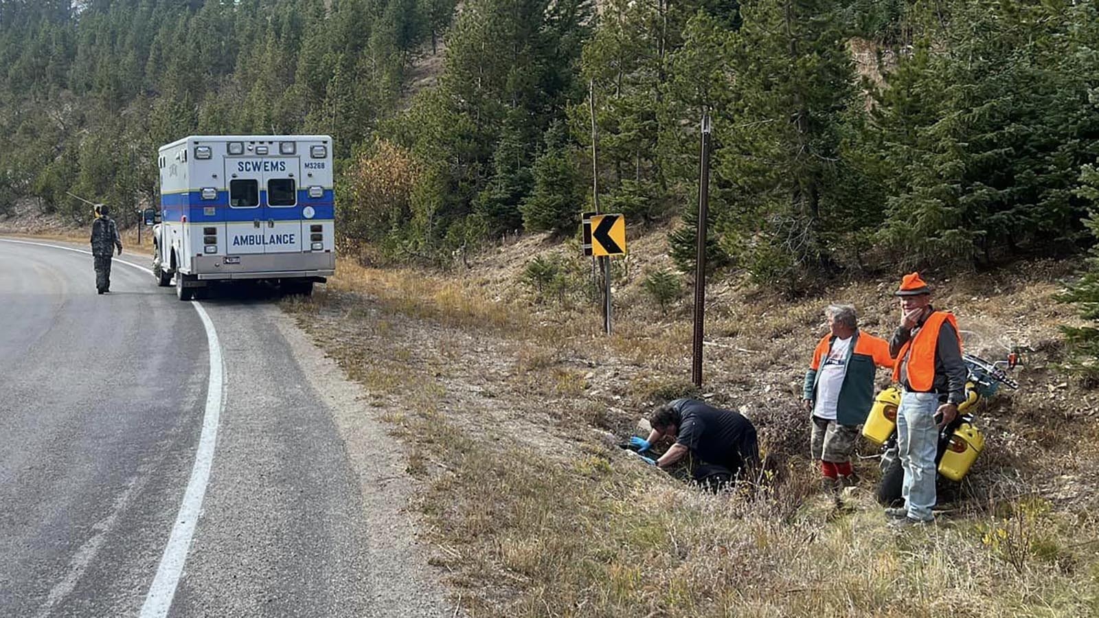 Rescue personnel attend to Phil Bollinger, who got stuck headfirst in a culvert under his motorcycle after a crash on Wyoming Highway 70. He might have died there had a pair of local hunters not noticed his boot waving in the air to get their attention.