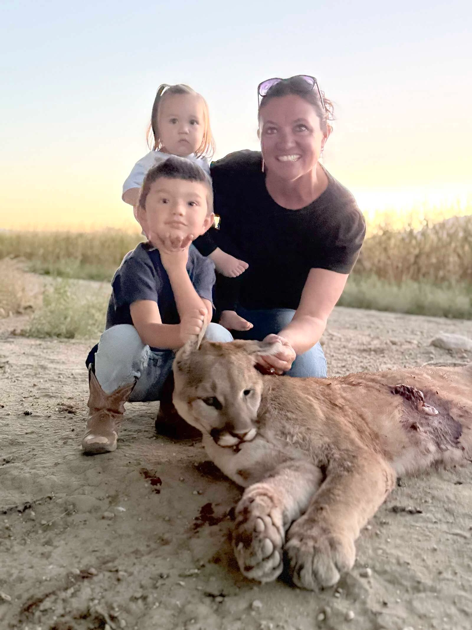 Bridget Gallagher, mother of nine and grandmother of four from Clark, poses with two of her grandchildren and the mountain lion she shot Tuesday near her family’s property.