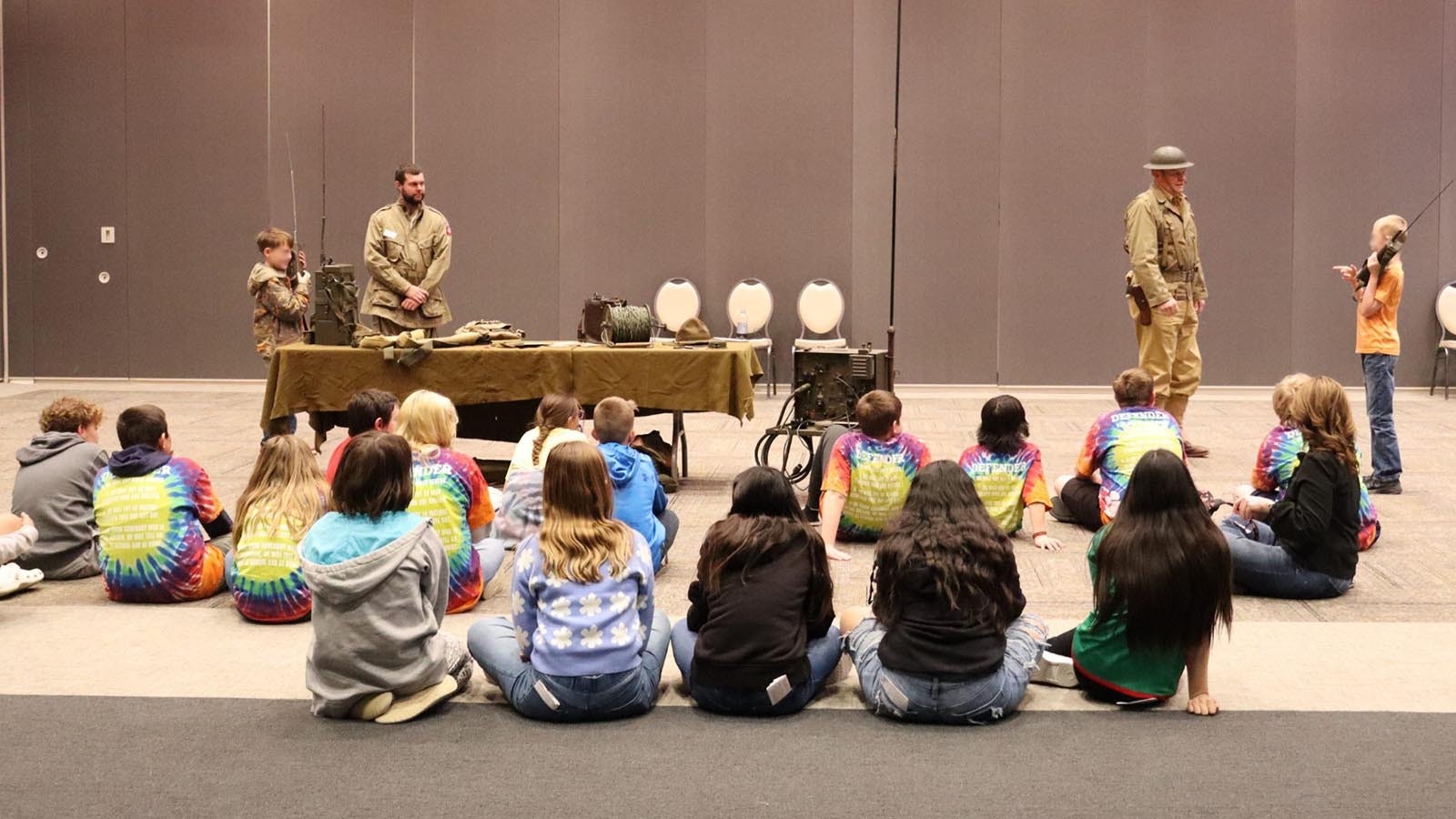 Justin Horn of the Rockpile Museum and Brig. Gen. Steve Mount, right, teach sixth grade students about war communication equipment.