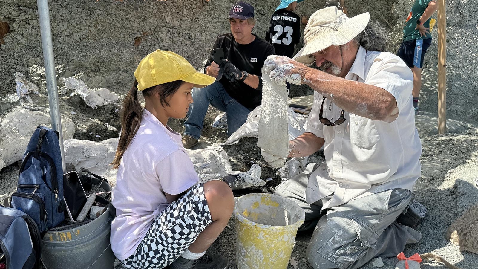 J.P. Cavigelli with the Tate Geological Museum in Casper teaches the jacketing process at the Nail Quarry. Strips of burlap are soaked in "pancake batter consistency" plaster and put over the top, around the edge, and underneath islands of rock containing Late Jurassic dinosaur fossils.