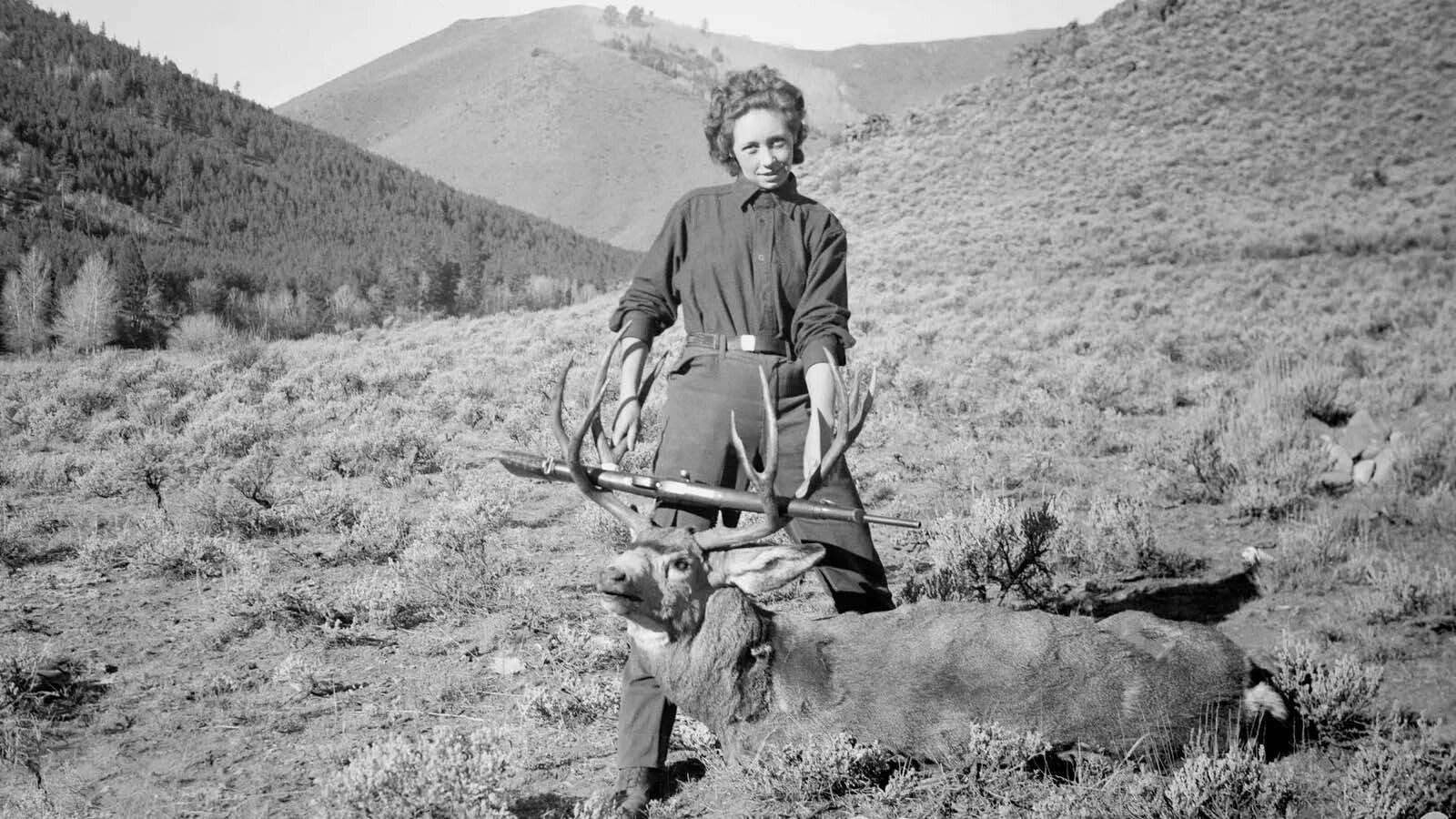 A girl shows off her trophy deer in this photograph by Lora Webb Nichols.