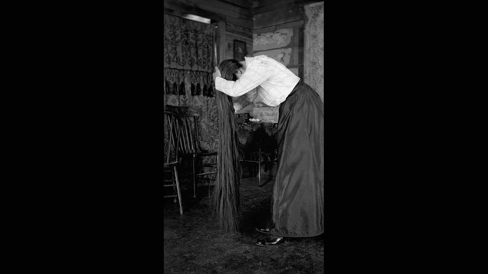 A woman combs out her long hair in this photo by Lora Webb Nichols.