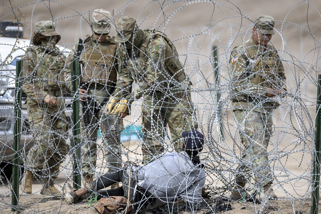 Texas National Guard troops try to untangle an immigrant caught in razor wire after he crossed the U.S.-Mexico border into El Paso, Texas, on Jan. 31, 2024, from Ciudad Juarez, Mexico.