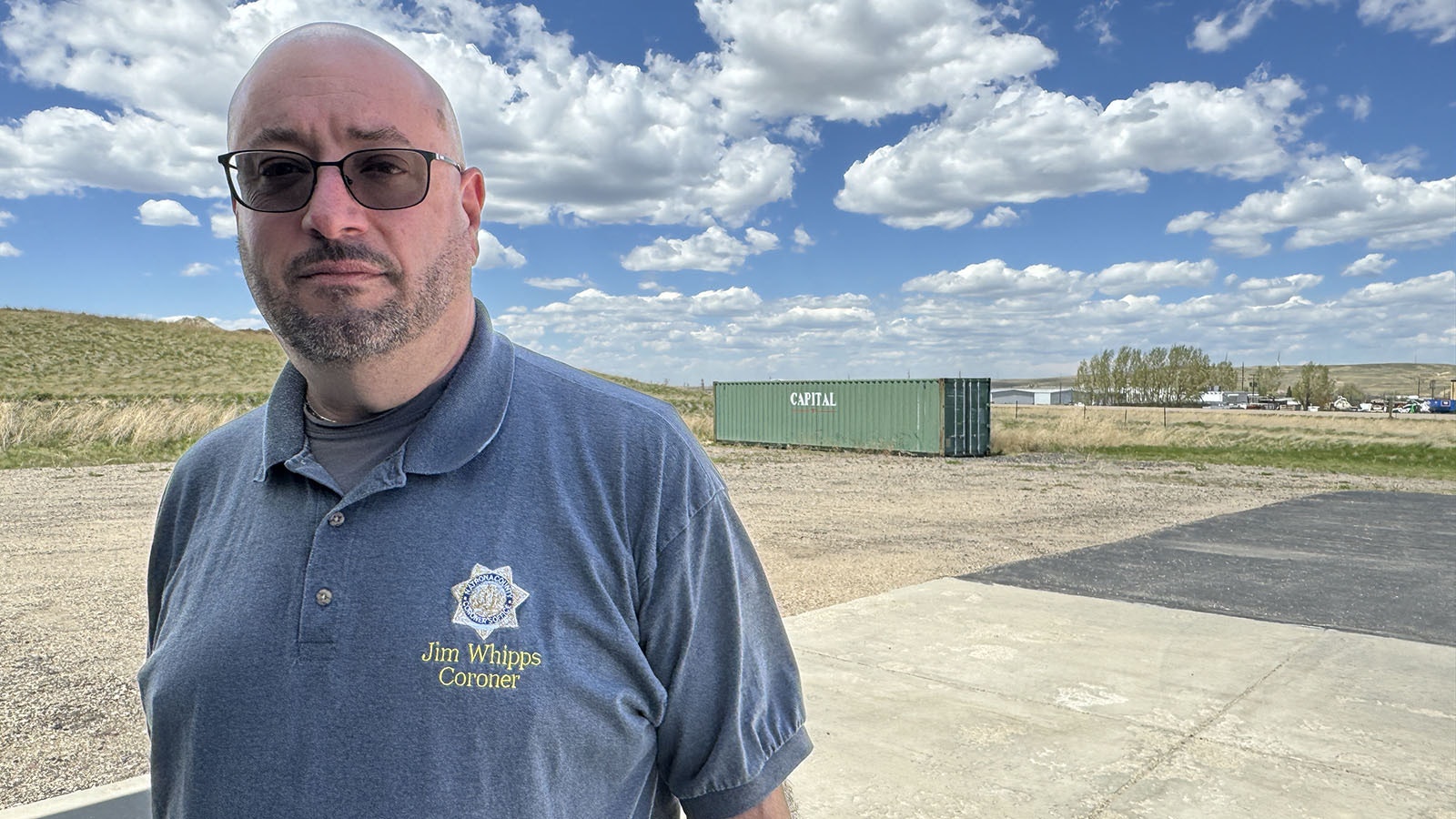 Natrona County Coroner James Whipps is dealing with having to find the next of kin for cremated remains of “indigent” people handed over to him by local funeral homes. The green intermodal container behind him is filled with coroner archives that he considered moving out to make room for the cremated remains of local people when he first learned in late 2022 that he might have his hands full.