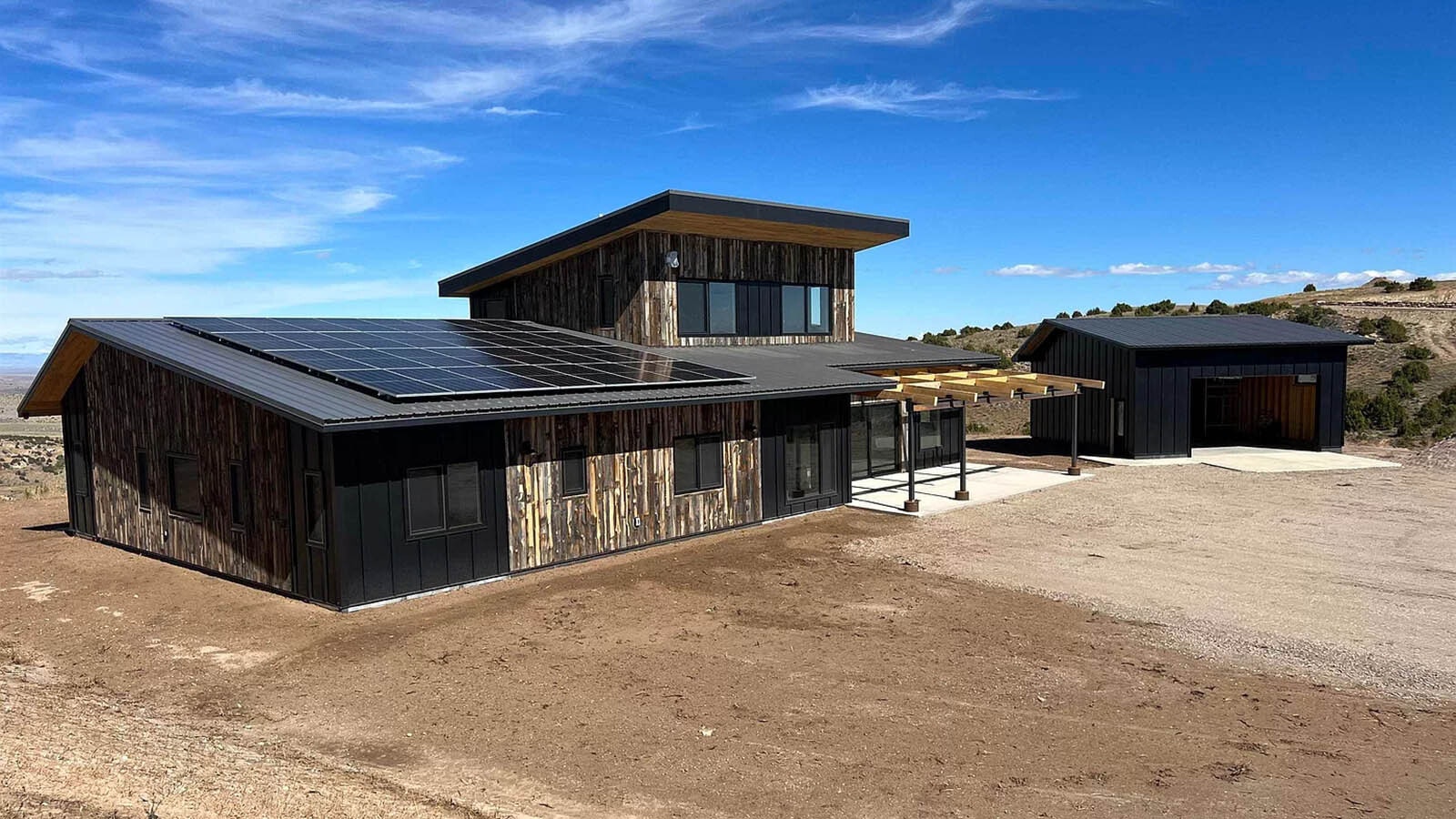 The net zero house has a modern look with materials and design that fit well with Wyoming and a rural landscape.