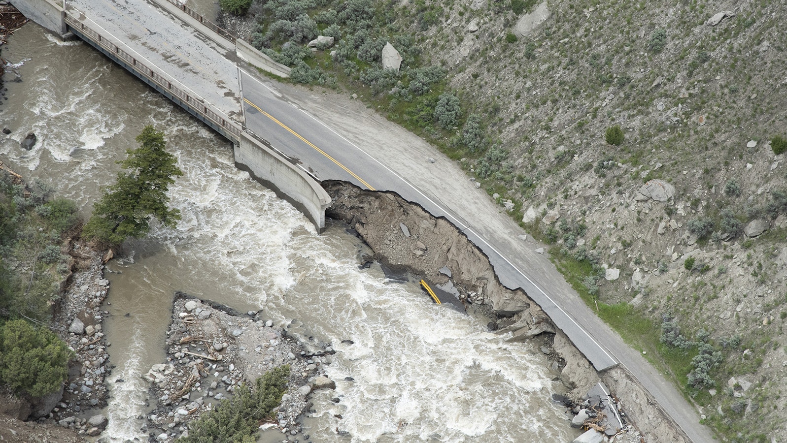 The Gardner River runs past washed-out sections of North Entrance Road following historic flooding in Yellowstone National Park that forced it to shut down June 19, 2022, in Gardiner, Montana.