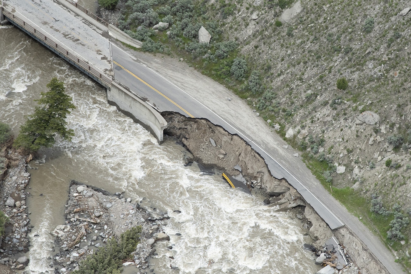 The Gardner River runs past washed-out sections of North Entrance Road following historic flooding in Yellowstone National Park that forced it to shut down June 19, 2022, in Gardiner, Montana.
