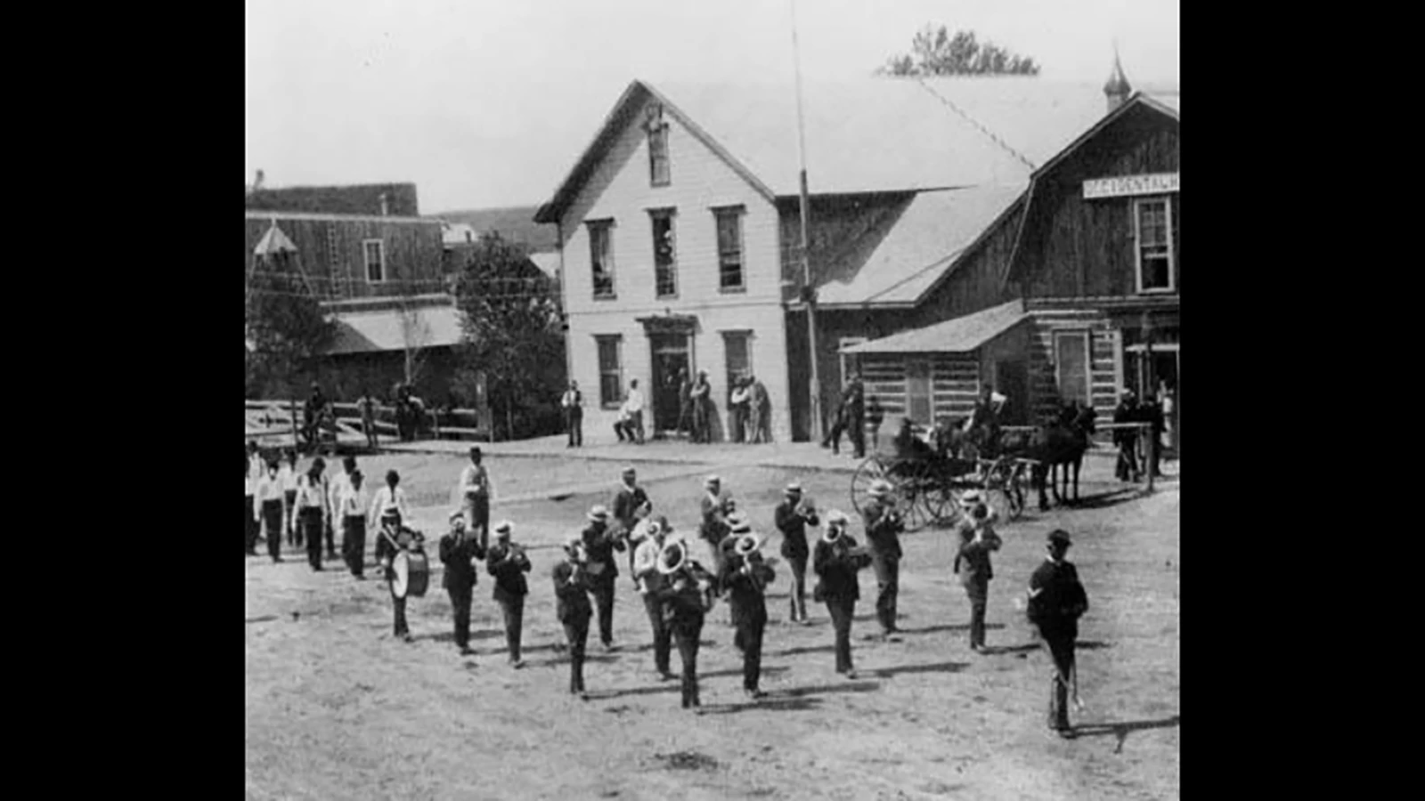 Marching band in front of the log Occidental, celebrating the Fourth of July in 1888. The original hotel was torn down in 1906 and replaced with a more modern brick building.