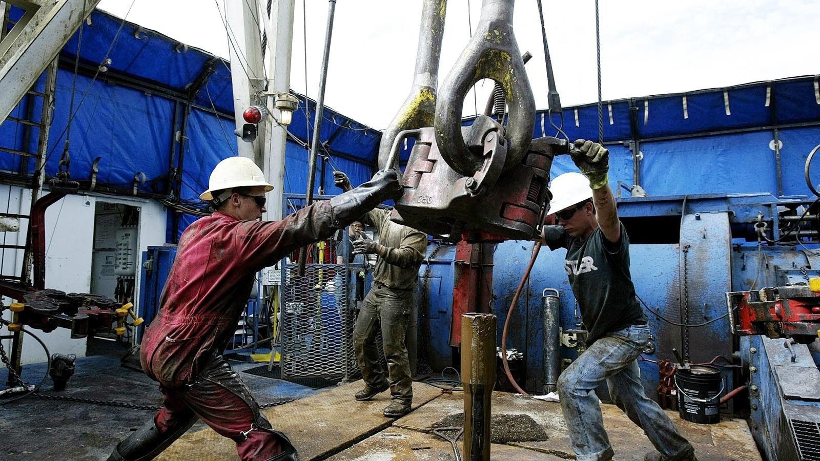 On the floor of a natural gas drilling rig, roughnecks move 25-ton blocks over a section of drilling pipe 8 miles north of Evanston, Wyoming, in this file photo.