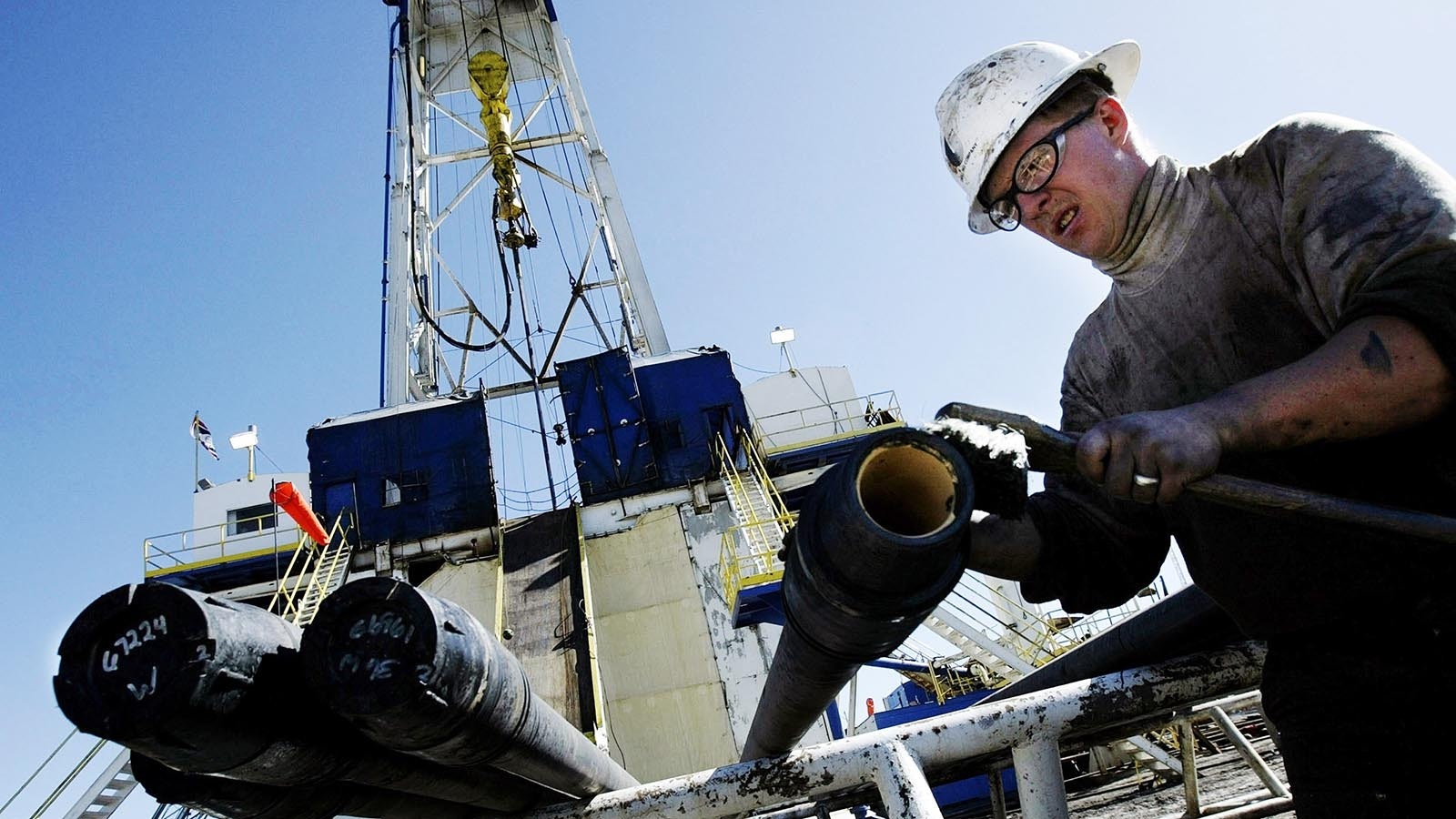 Below a natural gas drilling rig, a roughneck cleans the threads of a new section of 30-foot drilling pipe 8 miles north of Evanston, Wyoming, in this file photo.