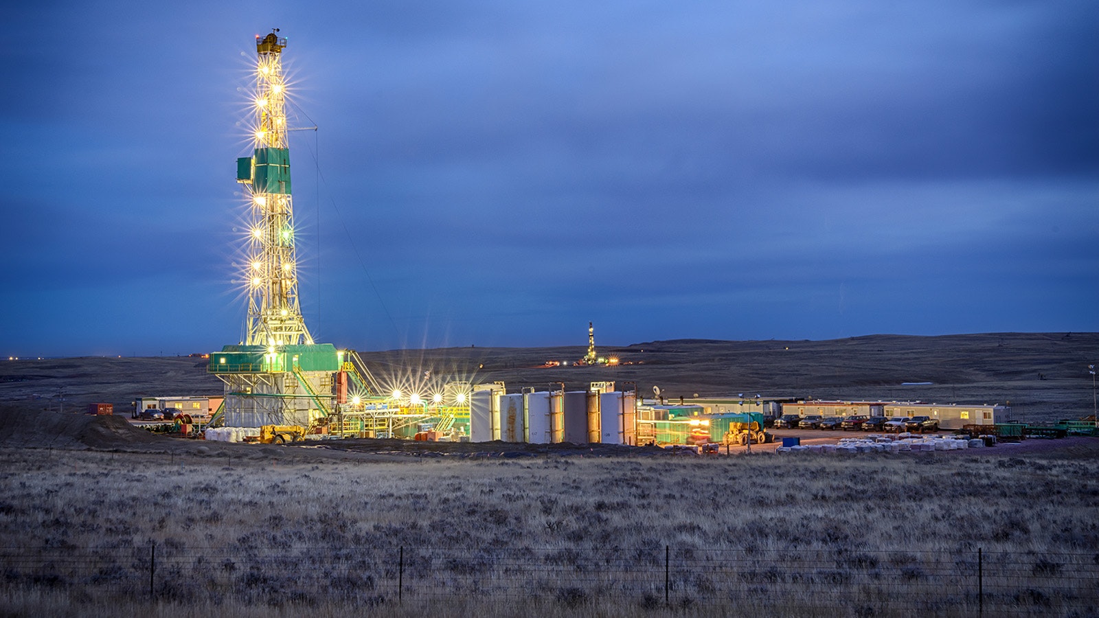 An oil rig is all lit up at night in a Wyoming oil field.