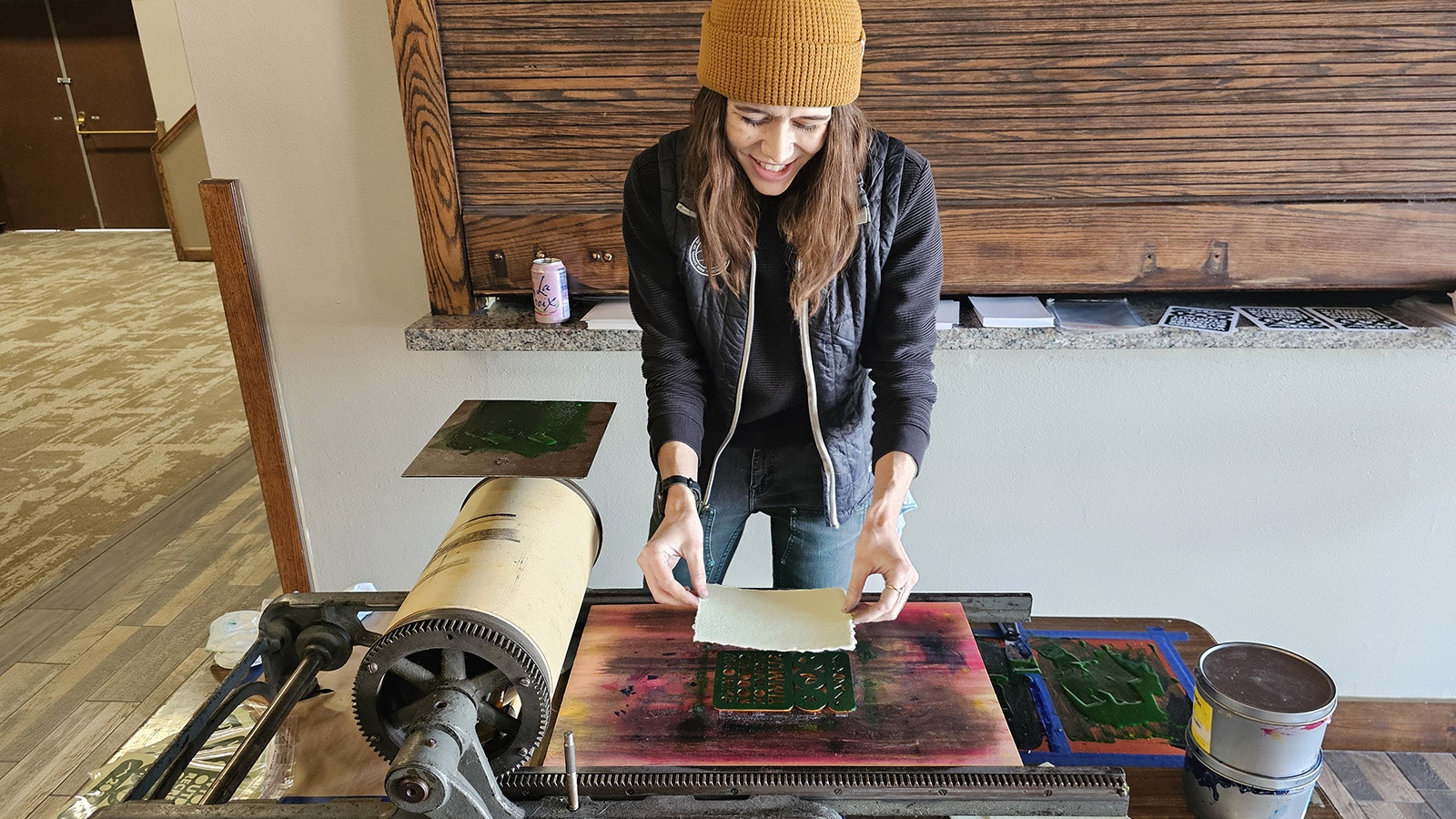 Kayla Clark carefully places a sheet of porous handmade paper on top of the laser-cut stencil she's inked.