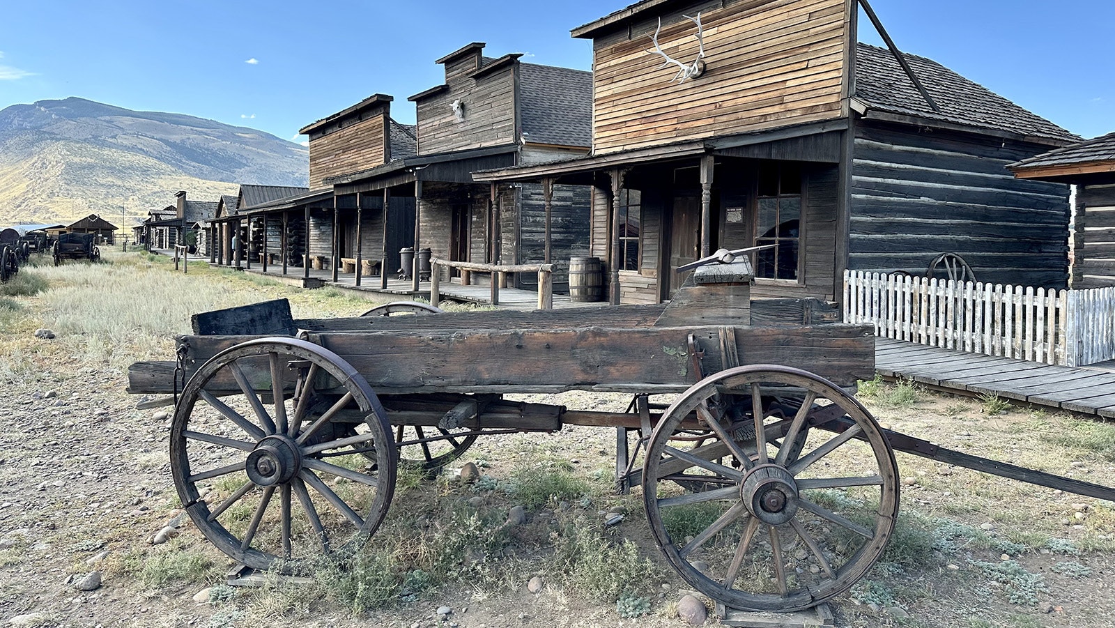 A wagon in front of a row of historic Old West buildings at Old Trail Town. There are 28 buildings, dating from between 1879 and 1901, and over 100 historic horse-drawn vehicles.