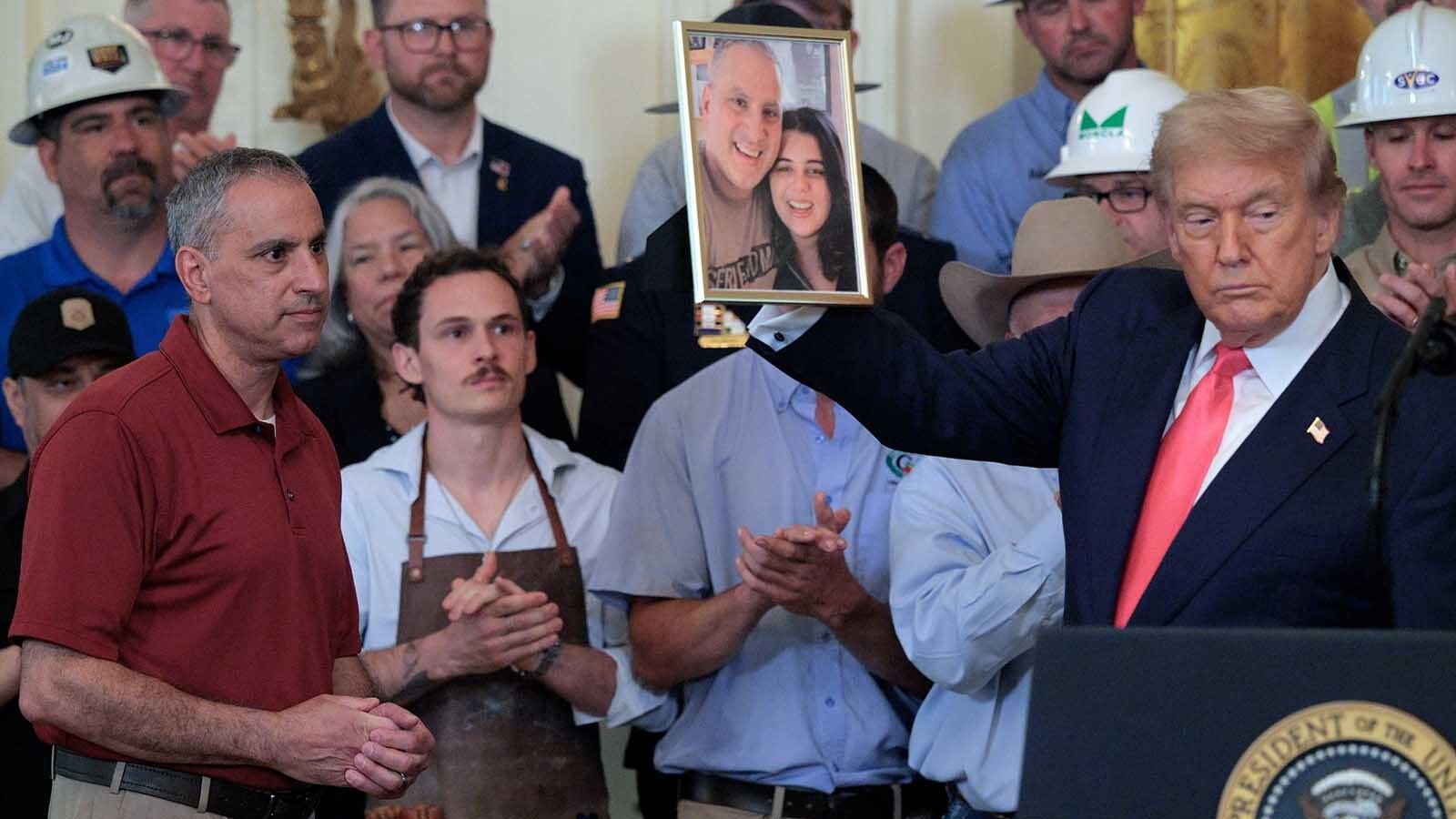 U.S. President Donald Trump holds up a photograph of Joe Abraham, left, and his daughter Katie Braham during a One, Big, Beautiful Bill event in the East Room of the White House on Thursday, June 26, 2025 in Washington, DC. Braham and her friend Chloe Polzin were killed in a car crash with an undocumented migrant earlier this year. Trump held an event to urge the passage of the One, Big, Beautiful Bill Act, Trump's signature tax-and-spending agenda.