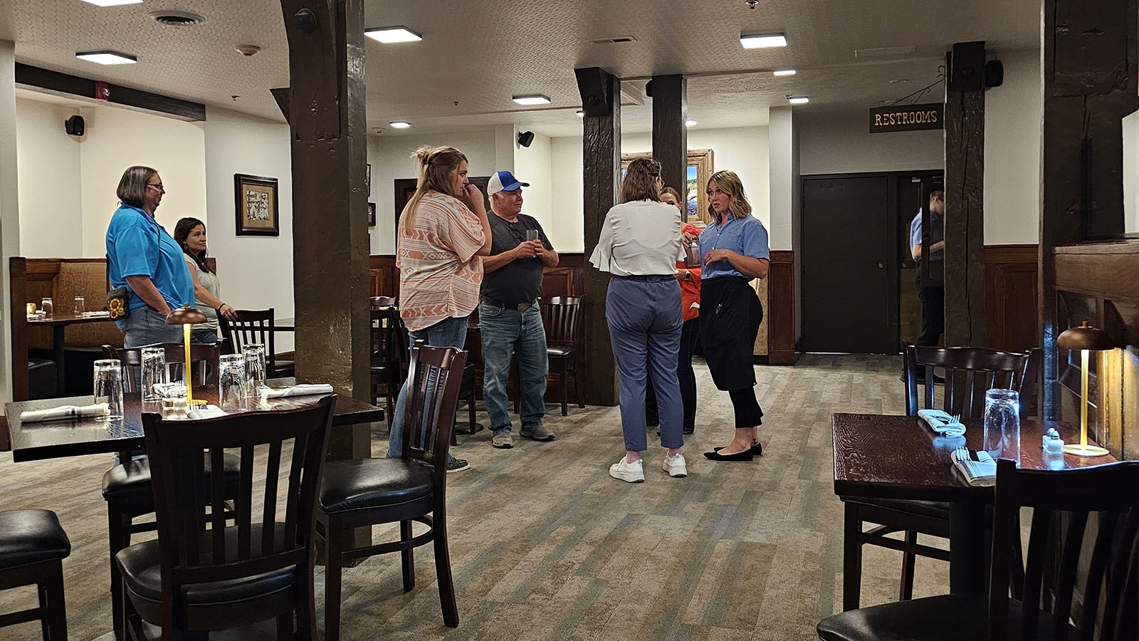 A group of customers discuss with Jessica what they saw happen to a glass on the table in the bottom right corner of this photo.