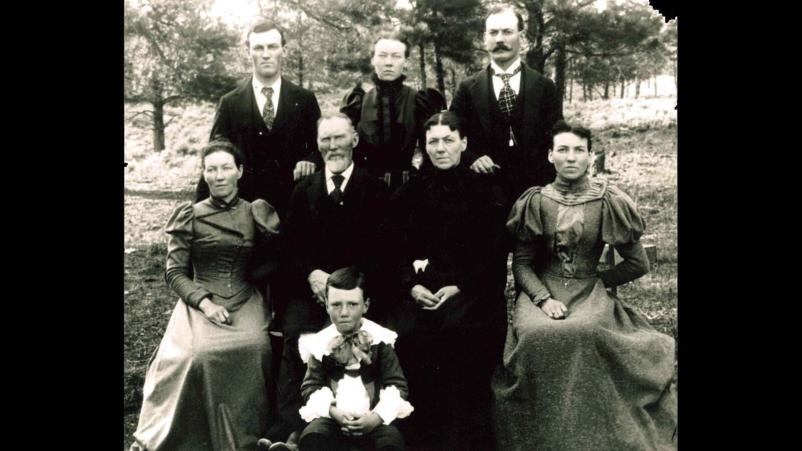 In 1888, Alfred Nelson (sitting, middle row), brought his two sons, Dick and Frank (standing) with him to visit their closest neighbors, men that were known to be fugitives from the law. He wanted to share the Christmas cheer with Buck Hanby and his small gang.
