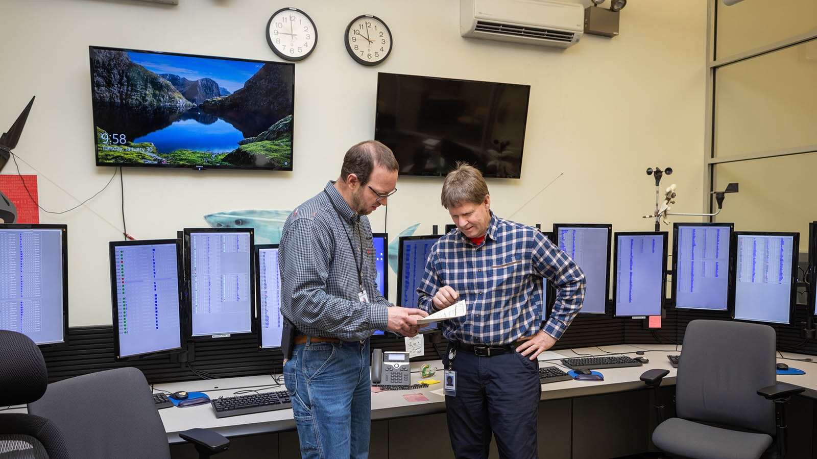Devin Hutchinson, left, and Laine Anderson review a wind farm map in "the fishbowl" at PacifiCorp's wind turbine Mission Control center in Casper.