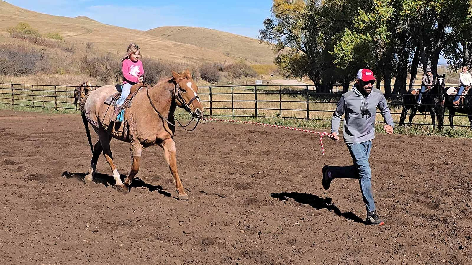 Richie Bratton runs ahead of his daughter, Dorothy's horse, Sweetgrass, because the horse was much more interested in munching on grass than running barrels.