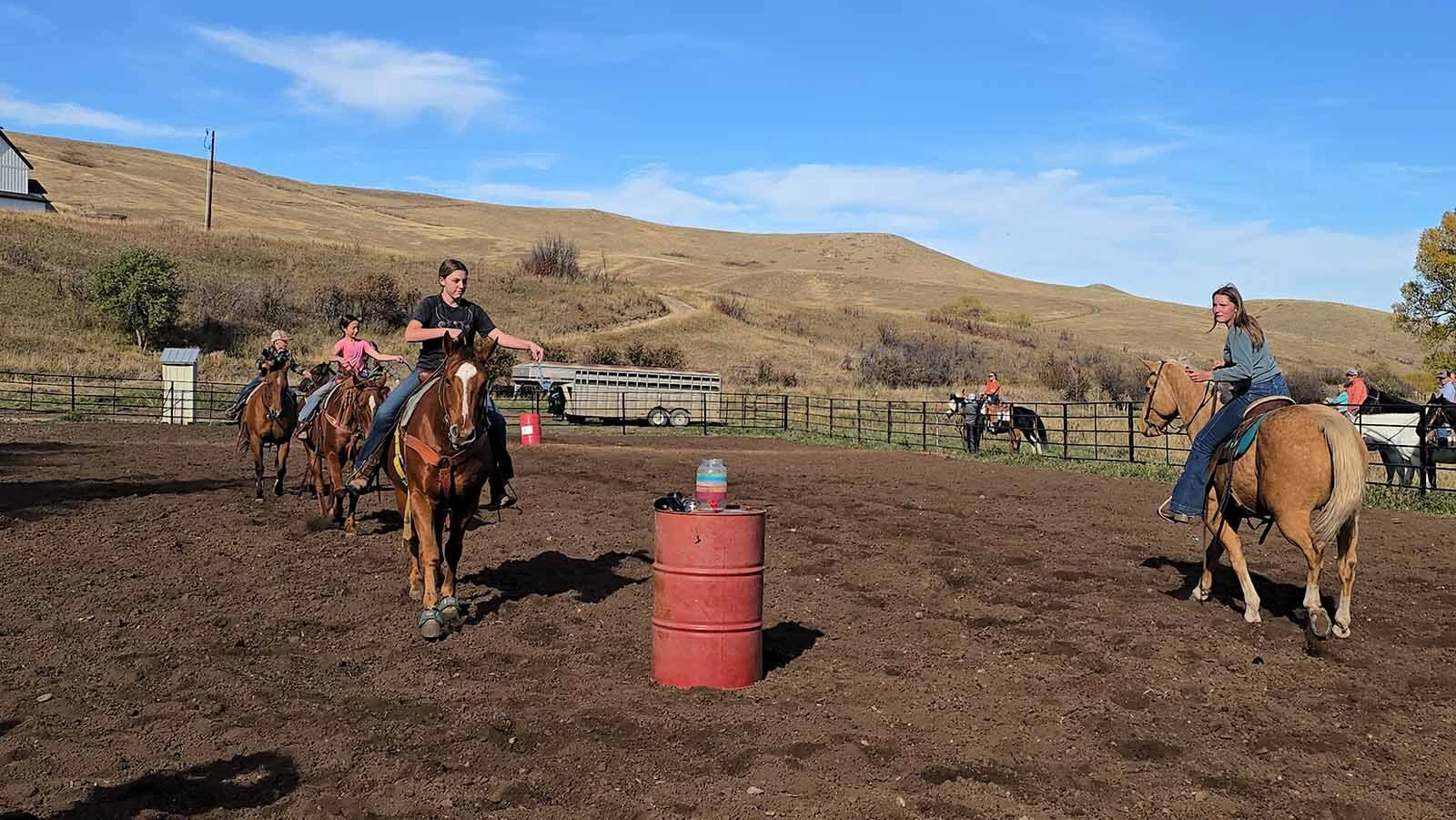 A team of riders attempts to fill a jug with water using a ladle. Eventually, one of the horses knocked the water jug over.