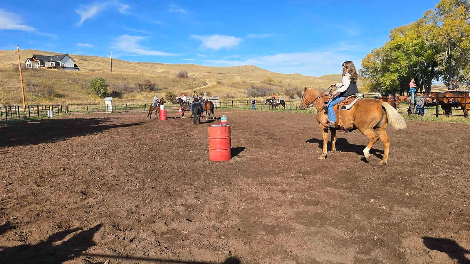 A team of riders attempts to fill a jug with water using a ladle. Eventually, one of the horses knocked the water jug over.
