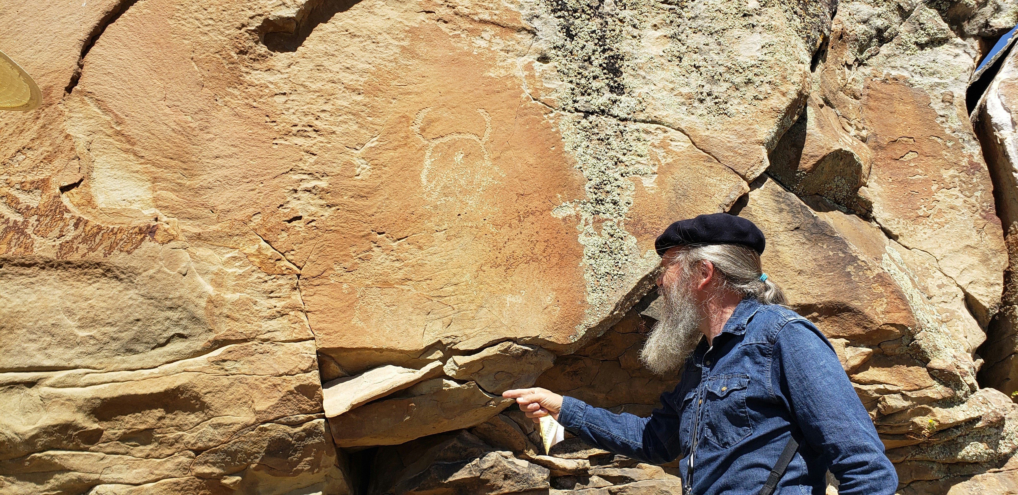 Barrie Lynn Bryant a documentary photographer points to a sandstone slab that is falling off. Bryant said the slab was not loose the last time he and Mike Bies checked on the petroglyphs. Drought has been hastening the disintegration process.