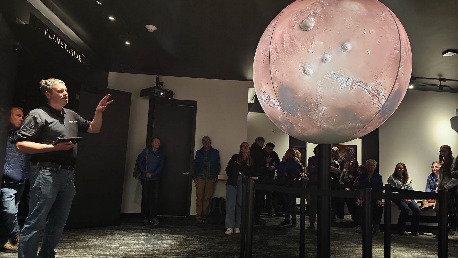 Director Joe Zator, center, talks about Mars and why it doesn't have an atmosphere while Earth does. Part of it is the planet's size. It's too small to retain the heat needed to keep its magnetosphere, and it didn't have enough gravity because of its small size to hold onto its atmospheric molecules either.