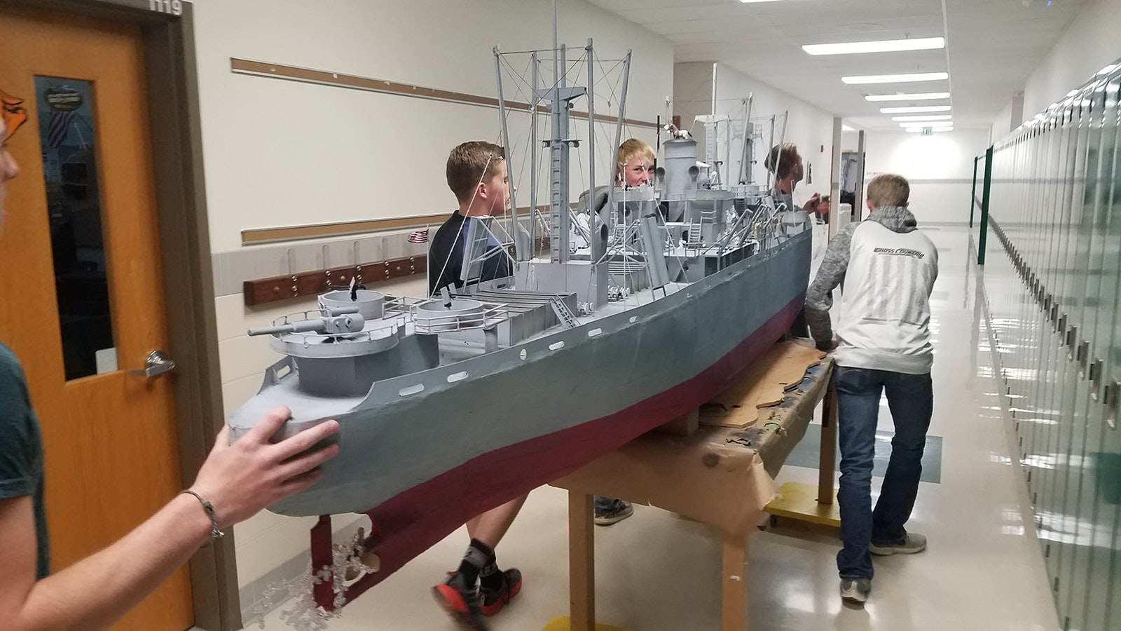 Students move one of the Liberty ships down the hall to the display area.