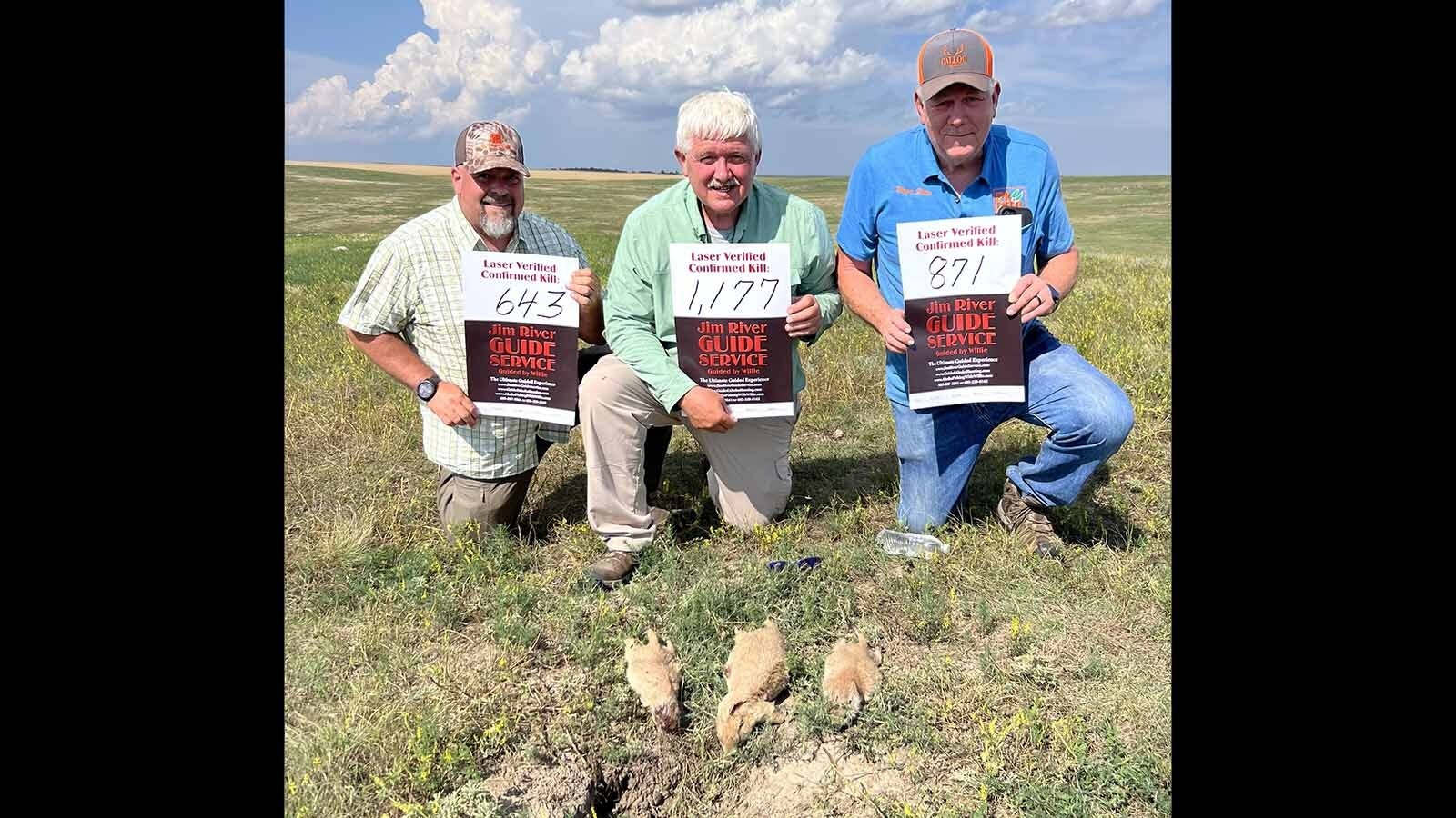 Prairie dog hunters in South Dakota hold up signs, indicating the distance, in yards, of the shots they made.
