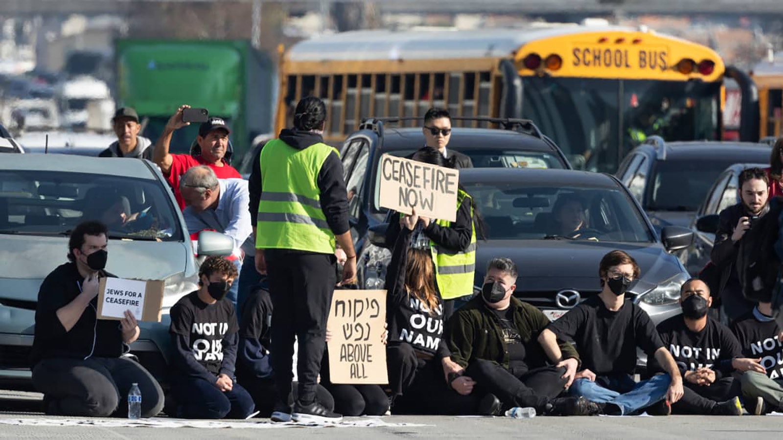 A group of demonstrators sit in the traffic lanes of the 110 Freeway in Downtown Los Angeles in December 2023.