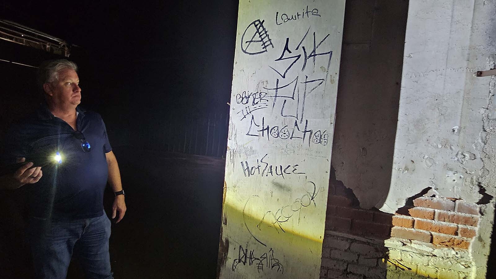 Cheyenne City Project Manager Paul Belotti shines a flashlight on some of the graffiti inside the Historic Pumphouse.