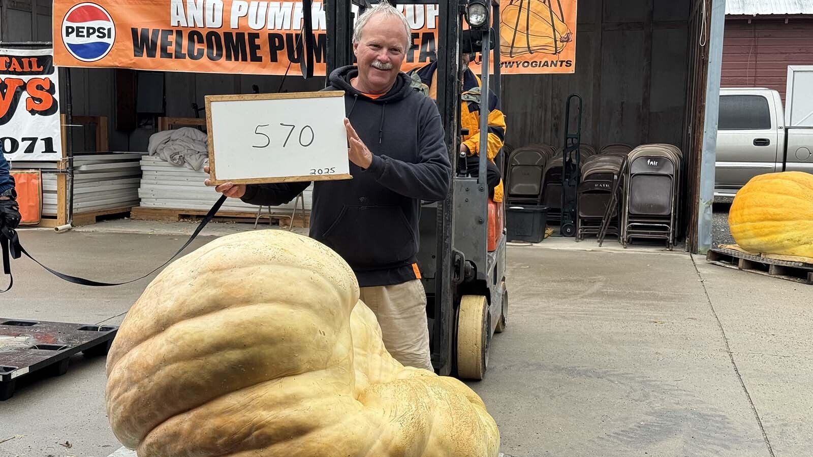 Jay Richard, "Wyoming's Pumpkin King," with his "570 pounds of ugly" pumpkin at the 2025 Wyoming Weigh-Off and Pumpkin Drop in Worland. "Jackie" was the fourth-largest pumpkin at this year's weigh-off, and Richard claimed the title of ugliest pumpkin of the year.