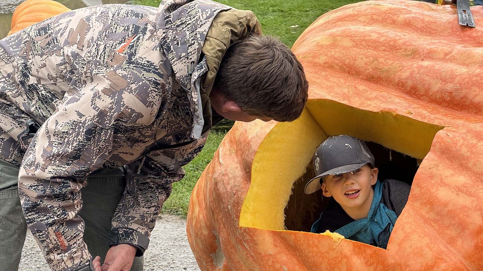 Chad Kurtenbach has a helper recover seeds from the interior of his 1,788-pound pumpkin during the 2025 Wyoming Weigh-Off and Pumpkin Drop in Worland.